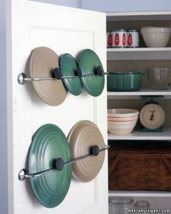 Organize pot lids in camper with curtain rods on the back of cupboard doors